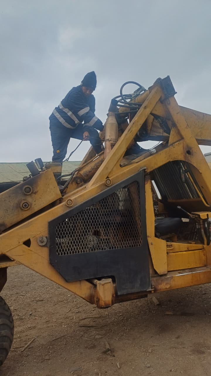 Auto electrician repairing wiring on a backhoe loader near Kokstad